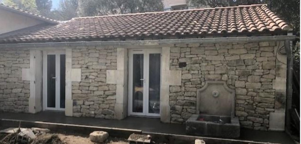 Mur construit avec des pierres à bâtir de la Drôme, encadrement de porte en pierre de taille et intégration d'une fontaine murale en pierre avec matériaux anciens LJLM matériaux anciens